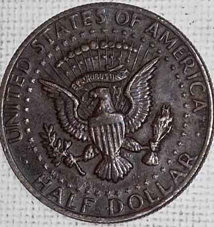 Kennedy half dollar missing obverse clad layer error showing exposed copper core compared to normal silvery clad reverse